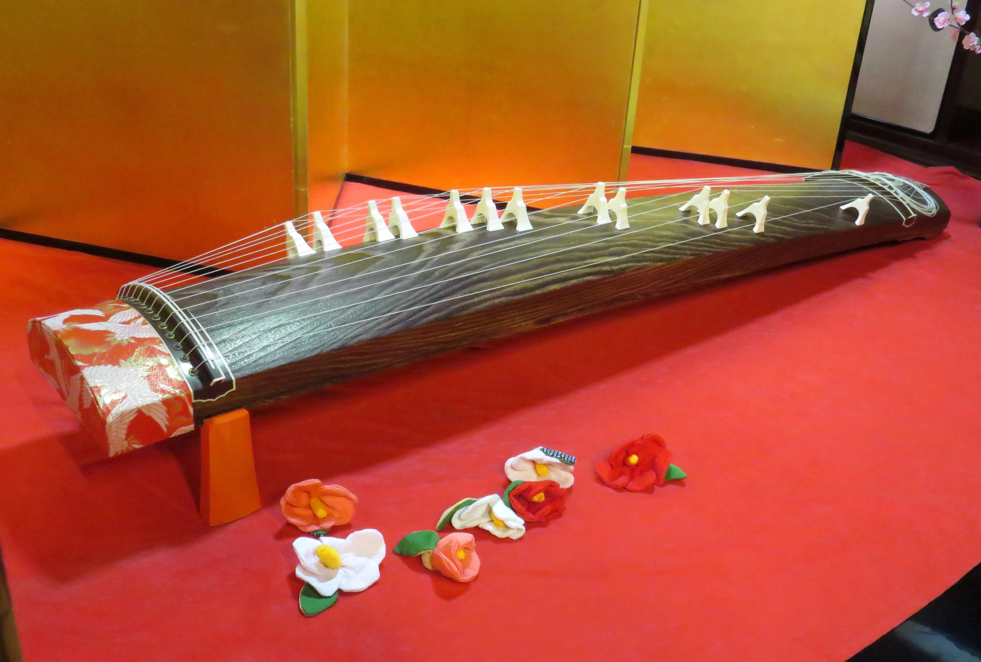 Traditional thirteen-string Japanese koto displayed on a red cloth